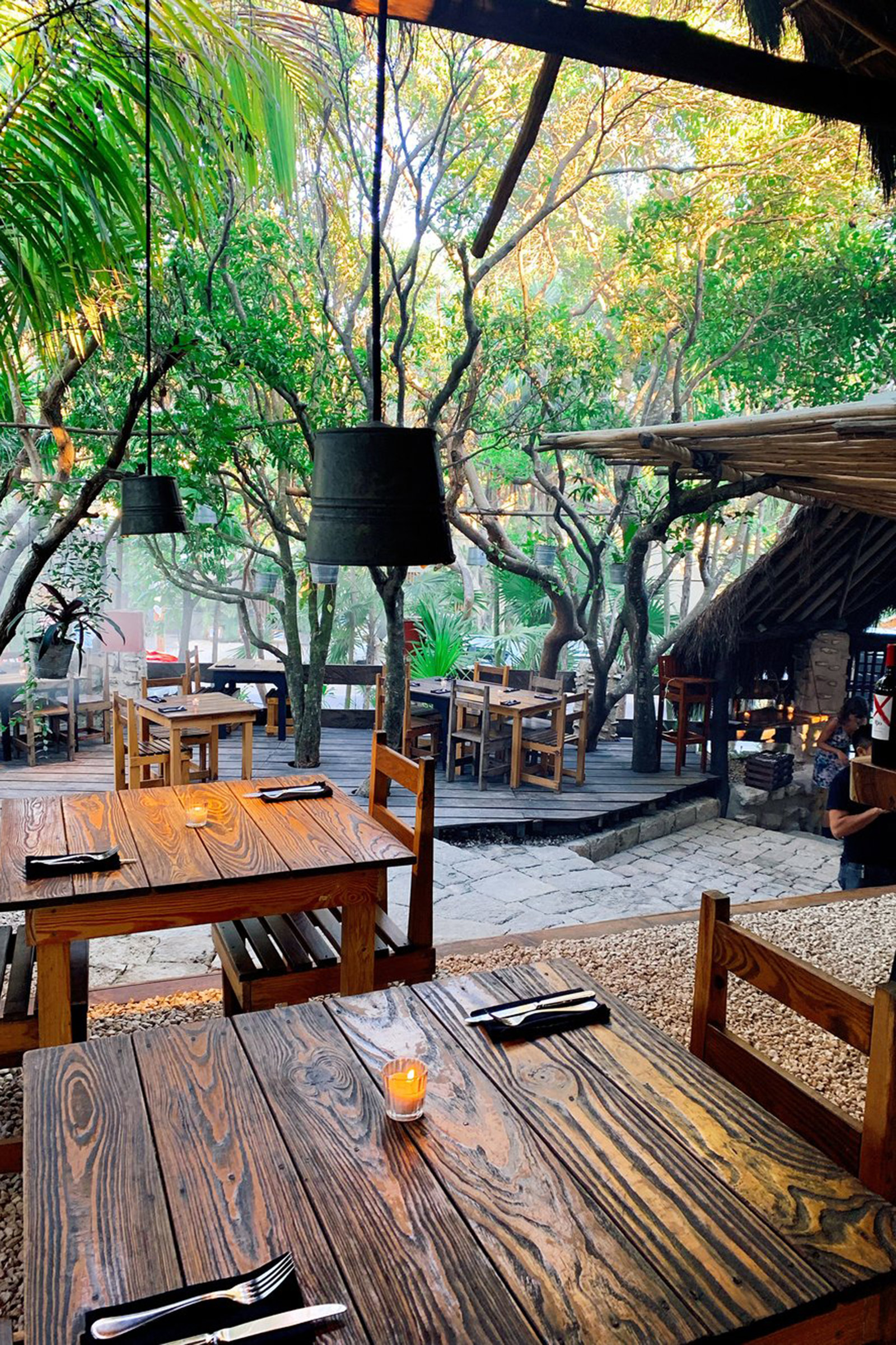 Authentically simple, both in aesthetics and cuisine, this palapa-housed restaurant reflects the true feeling of the Tulum jungle and the local culinary traditions. A few small tables under the overgrown trees and the extent use of wood allow Kitchen Table to be totally in tune with its natural surroundings, while using solar power for a sustainable future. - Image