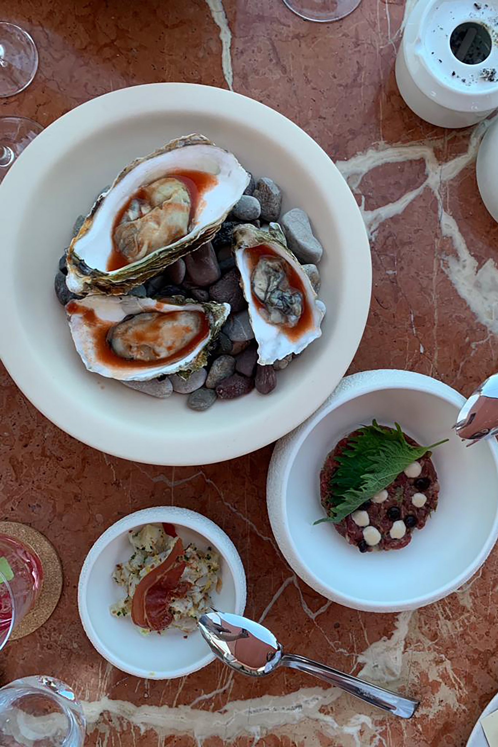 Fresh fish and seafood, raw and cooked, premium cuts, vegan delicacies, local and international ingredients, sophisticated cocktails and premium cuvees are served on both levels of the brand-new beach resto, which encapsulates the authentic Mykonos spirit in a boho-chic and luxurious manner. - Image