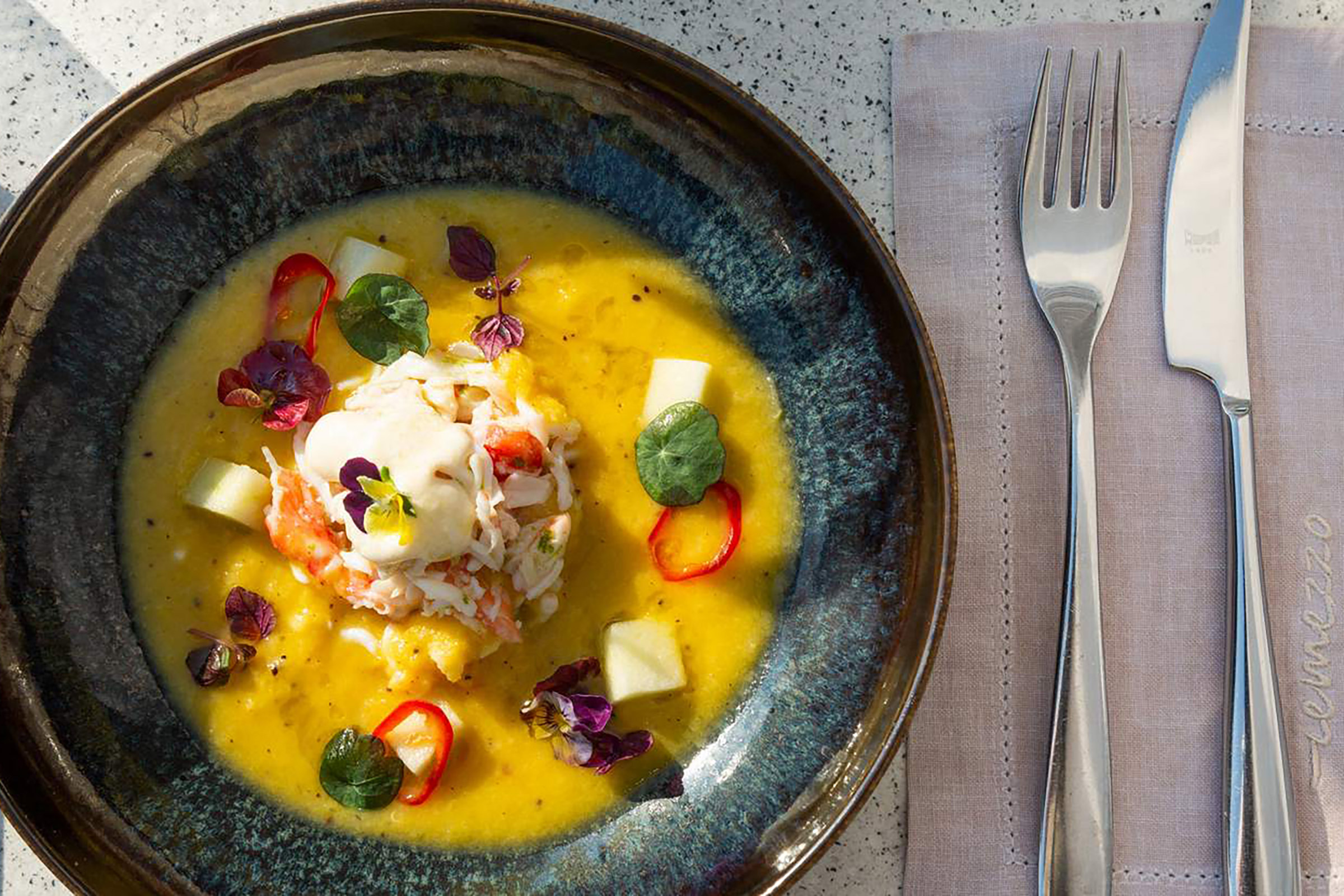 Here fine dining and drinking is combined with special DJ guests and glamorous parties, while the mesmerising view serves as the perfect background to the much-promising nights of the island of the winds. Greek gastronomic delights are the way to start your evening, paired with fine wines and champagne, while the best bartenders on the island await at the Remezzaki small terrace to please your most extravagant drinking wishes. - Secondary Image