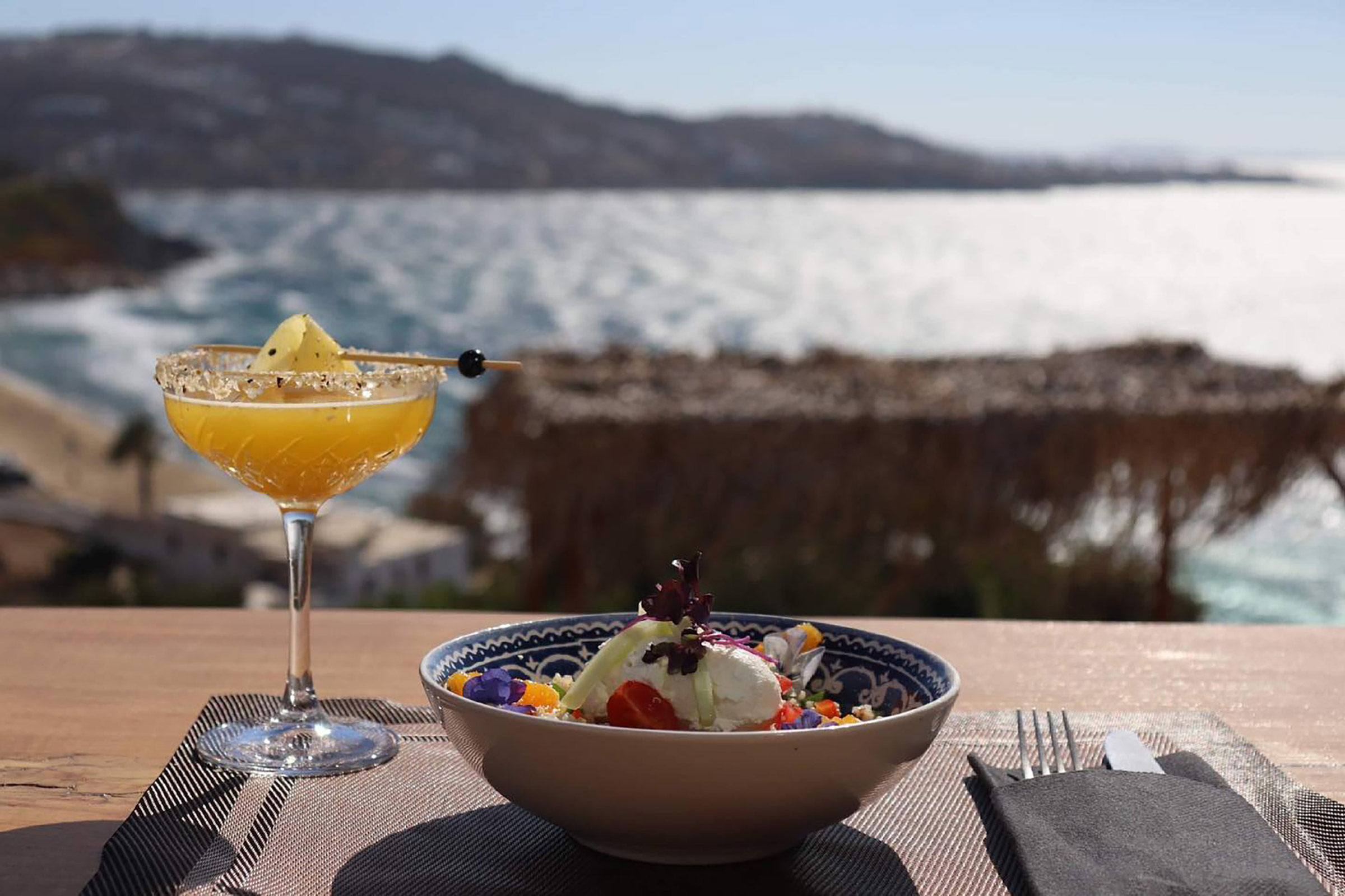 Relax on the designer chaise longues, facing the endless blue sea and the neighbouring islands, take a pick from the sophisticated classics or the tailor-made cocktails prepared in perfection with the finest spirits, freshest fruits and local herbs, treat yourself to an octopus carpaccio with avocado mousse or a black angus burger and surrender to the magical evening turning into night on one of the most beautiful islands in the world. - Secondary Image