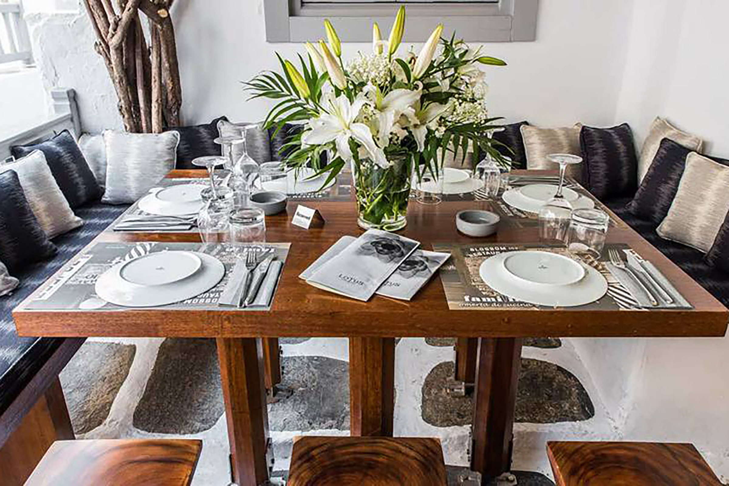 With its blooming huge bougainvillea standing against the white-washed walls and saluting its guests, and the candlelit ambiance preparing one for a romantic night out, joyful companies of friends, modern families and enamoured couples come here year after year for the delicious Greek and Mediterranean dishes, the wide wine selection, the inspired cocktail list, and the amazing music choices creating a unique ambiance of laidback luxury and unpretentious grace. - Secondary Image