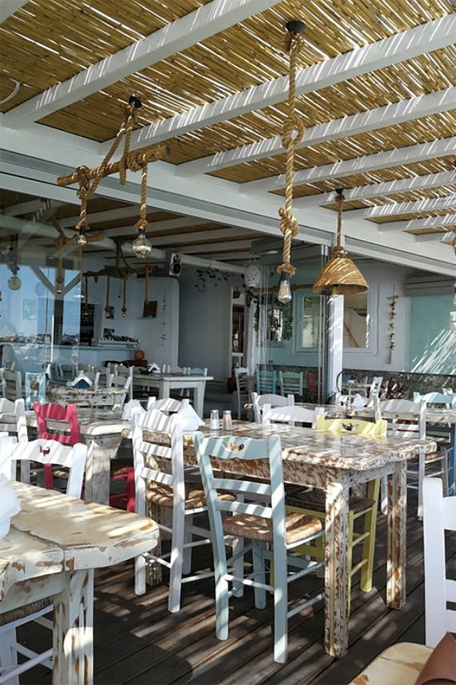 Located on the far end of the beautiful Aghios Stefanos beach, Taverna Petran (which actually means Peter’s tavern) is a typical Greek tavern on the sea, featuring whitewashed interiors, white wooden tables and traditional wood and wicker chairs and serving traditional taverna dishes. - Image