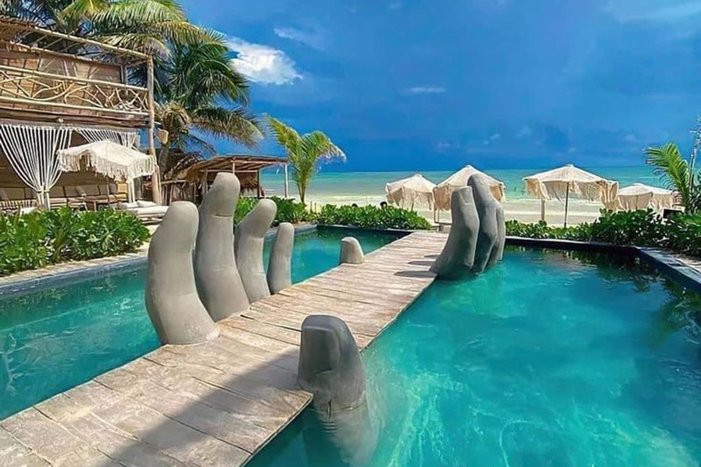 When reaching the entrance, a giant pair of wooden hands awaits to welcome you in the most mystical of ways and introduce you to the cool-vibed setting of this amazing beach club. Totally blending in with its natural surroundings, with wood, wicker, earthly tones and natural materials setting the design tempo, Vagalume will make you feel one with nature in the most luxurious of ways. - Secondary Image