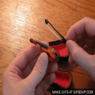 Man takes a little, tiny violin from its enclosure and pretends to play it.