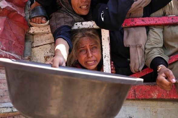 Palestinians struggling to get food. A woman holds out a tin bowl as a young girl stares at the camera in anguish.