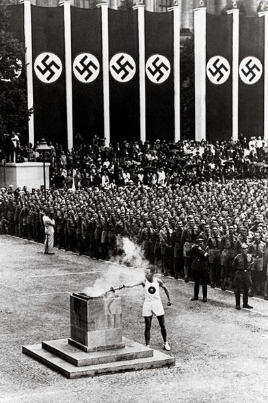 Swastikas line the background at the lighting of the Olympic torch at the 1936 Summer Olympics.
