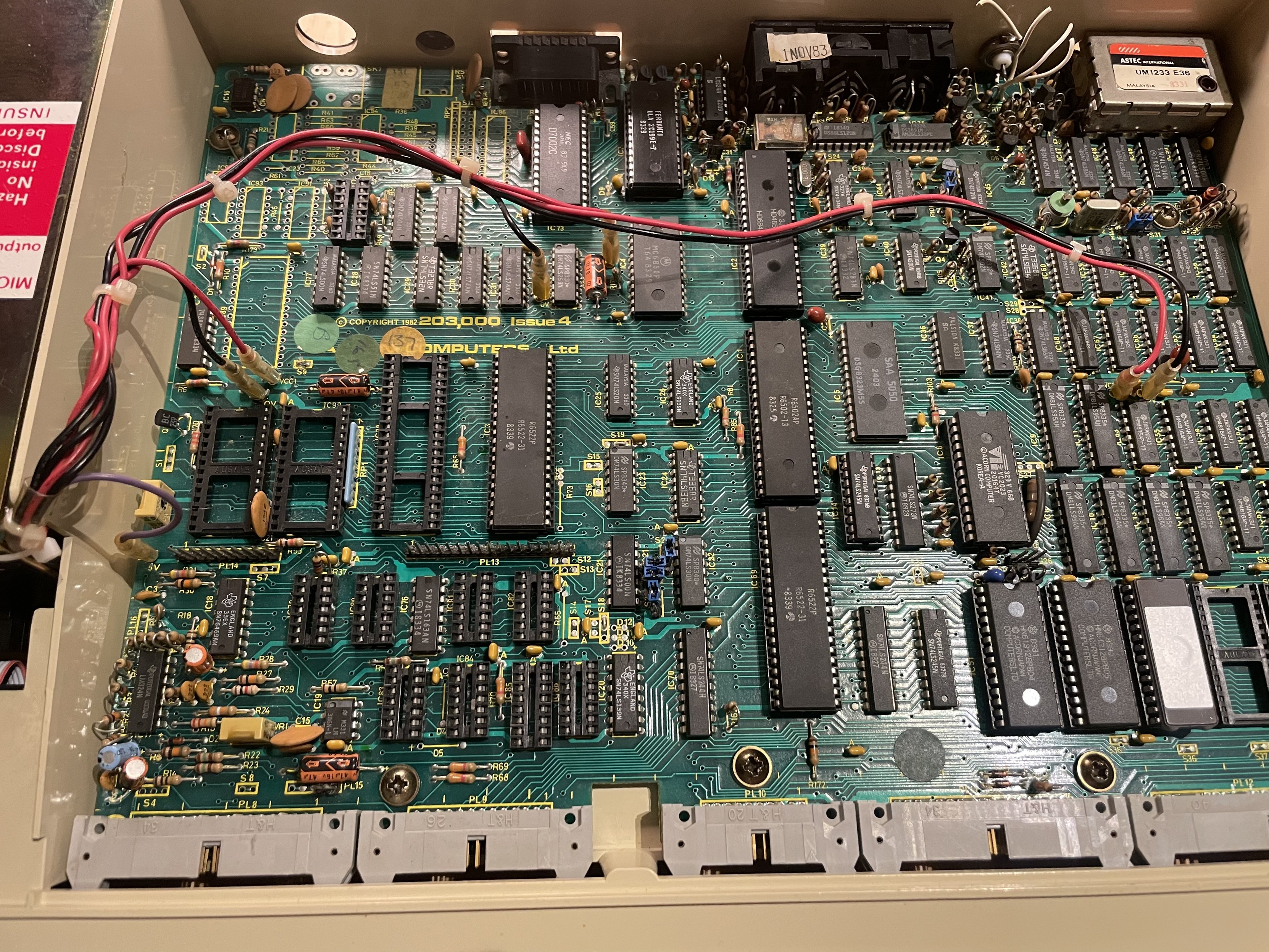 Photo of BBC Micro B motherboard showing the seven wires from the power supply connected to different parts of the board.