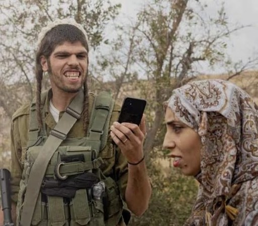 Armed Israeli settler (colonist, thug, thief) with the face of an aggressive baboon mocking a Palestinian woman while he films her. From the cover of L’Espresso magazine.