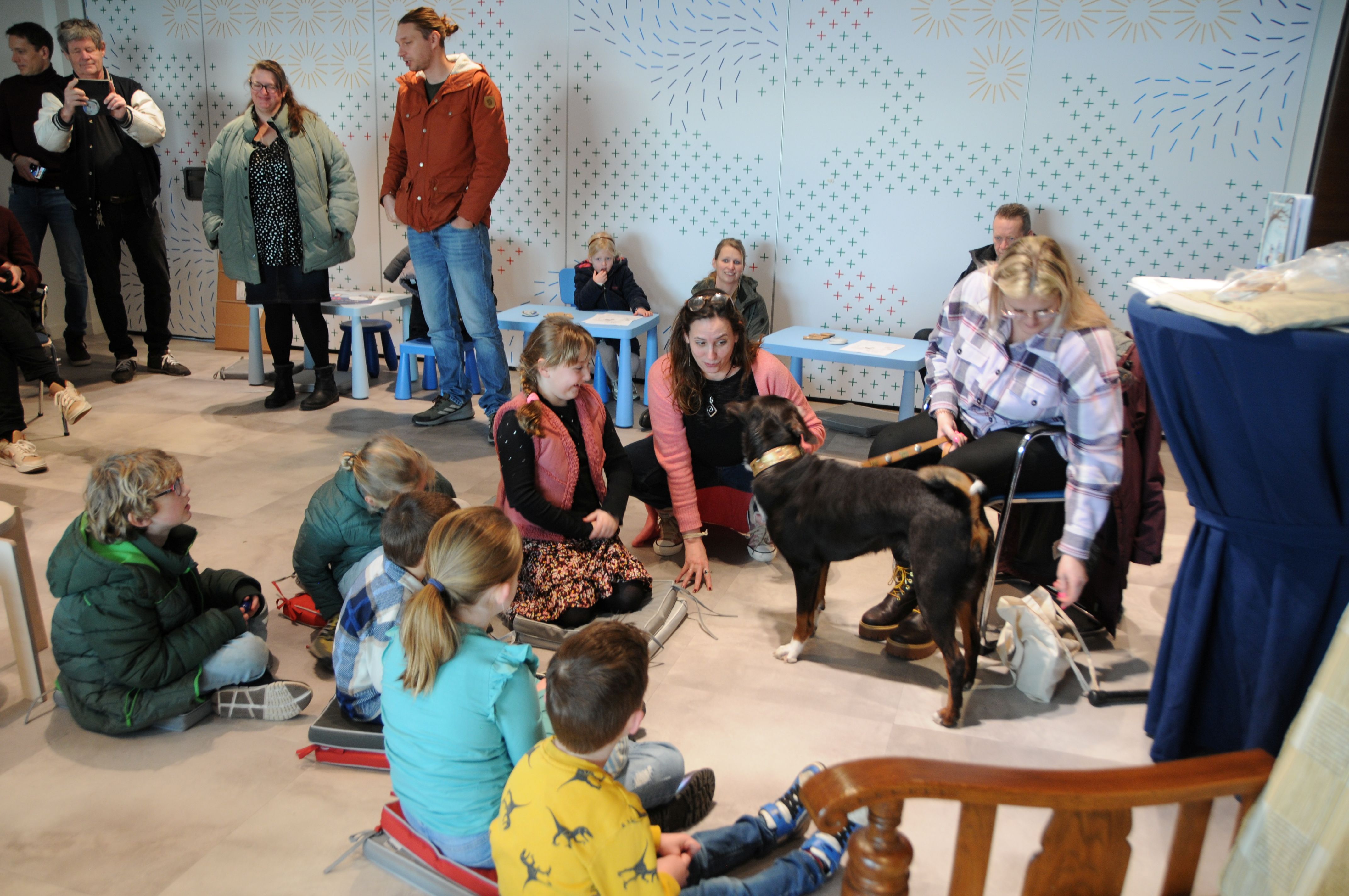 Kinderen zitten in een kring rondom een hond.