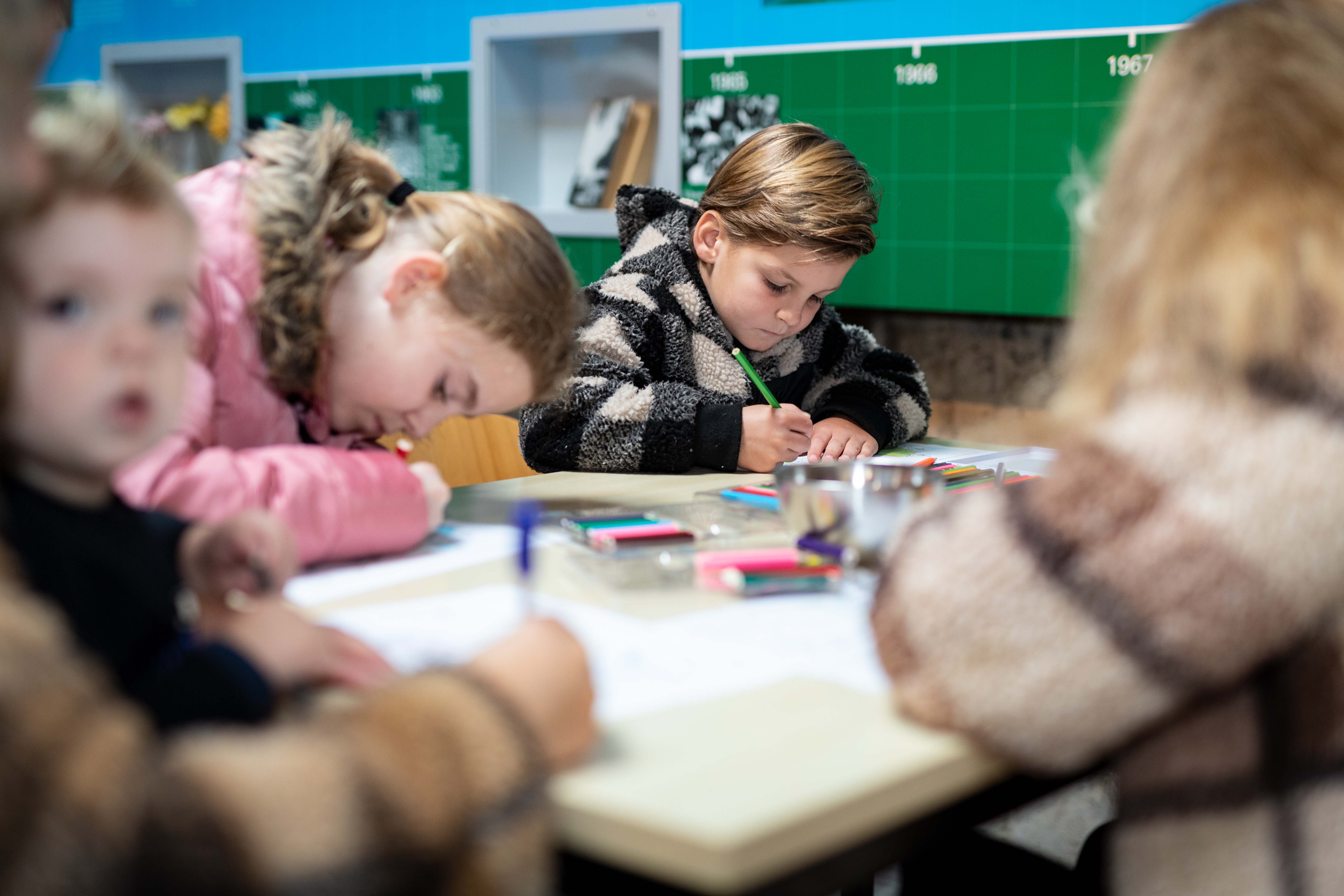Kinderen zitten te tekenen aan een tafel.