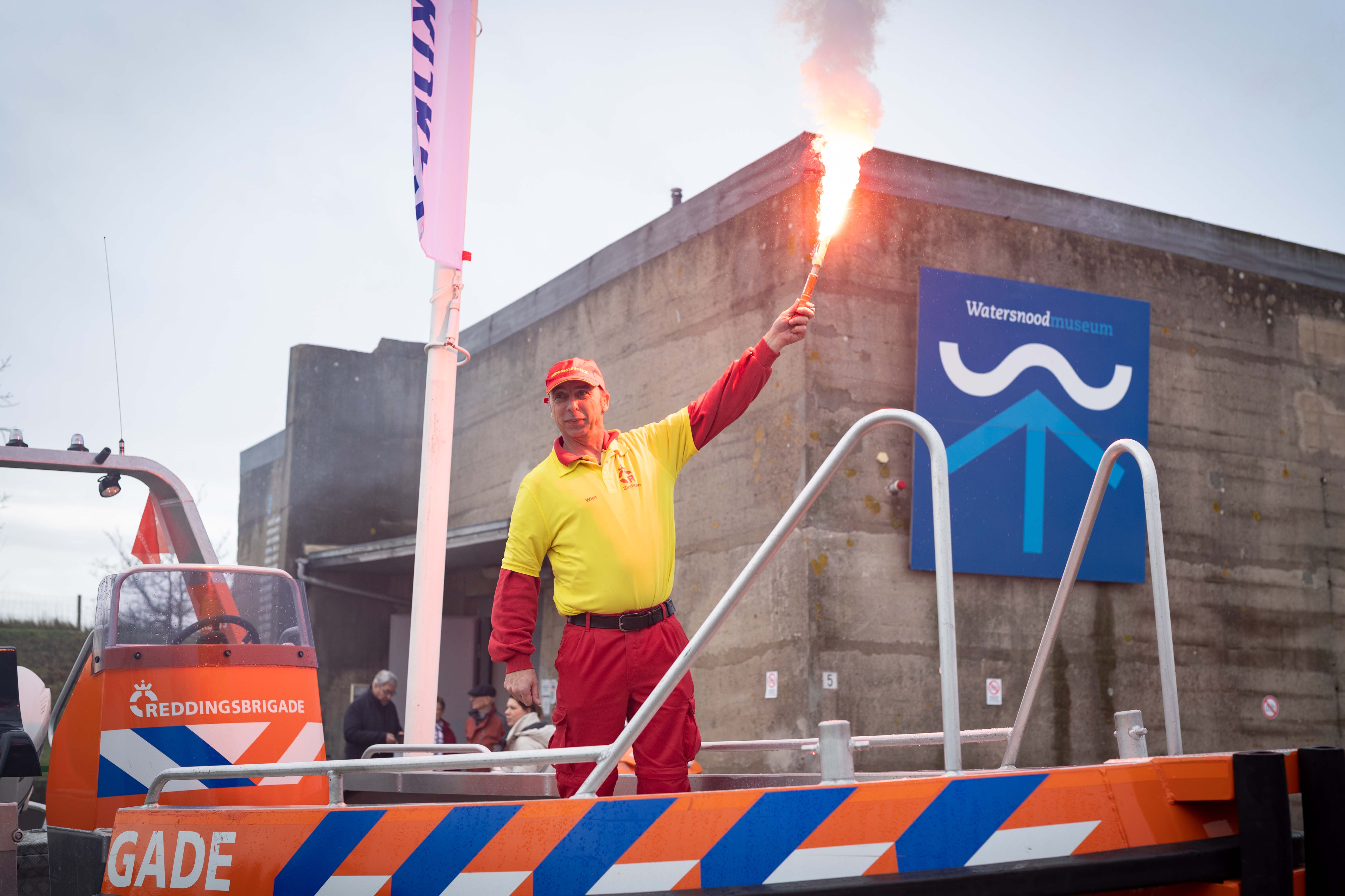 Man van de reddingsbrigade in een reddingsboot voor het watersnoodmuseum.