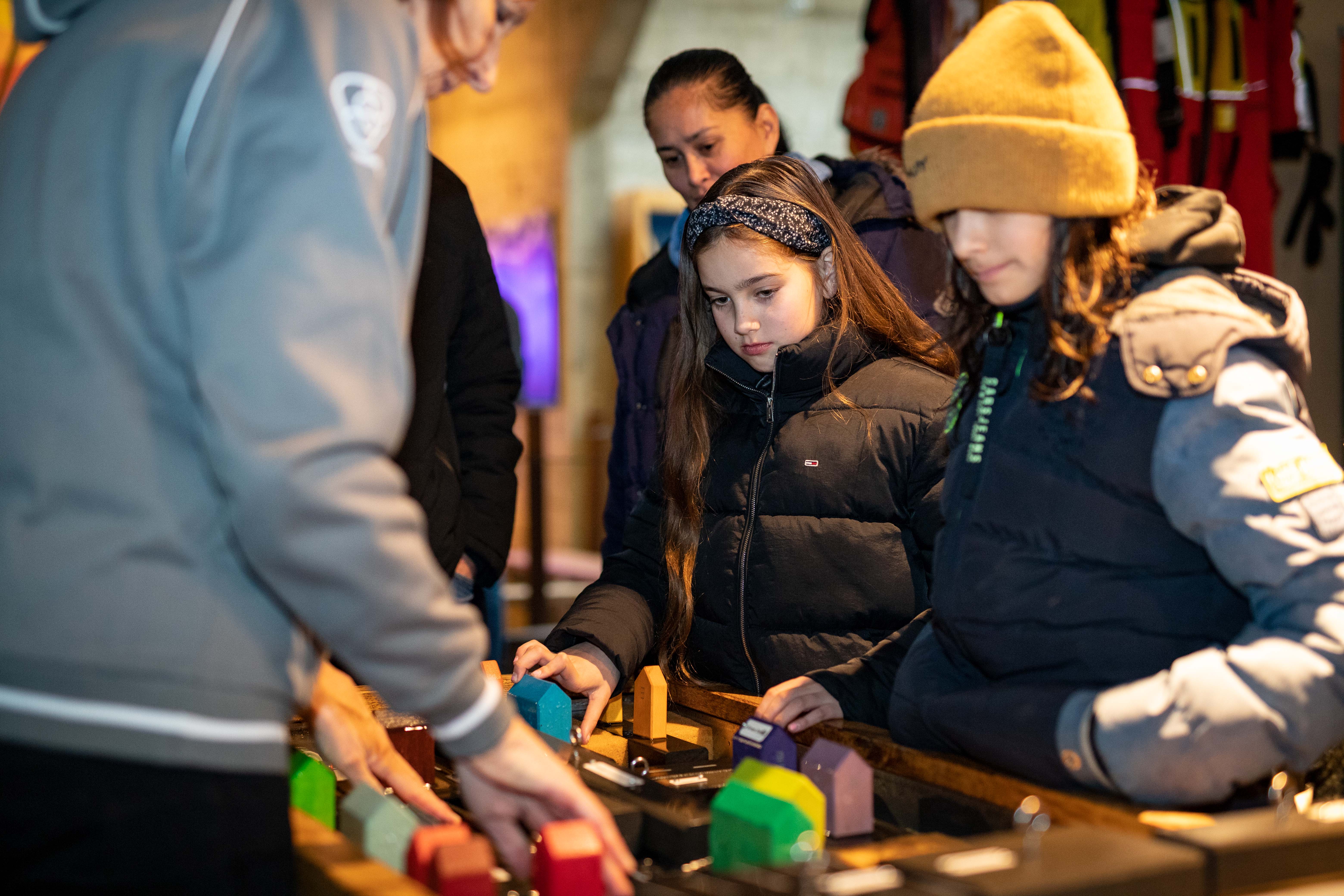 Kinderen kijken naar een tafel met een nagebouwde stad.
