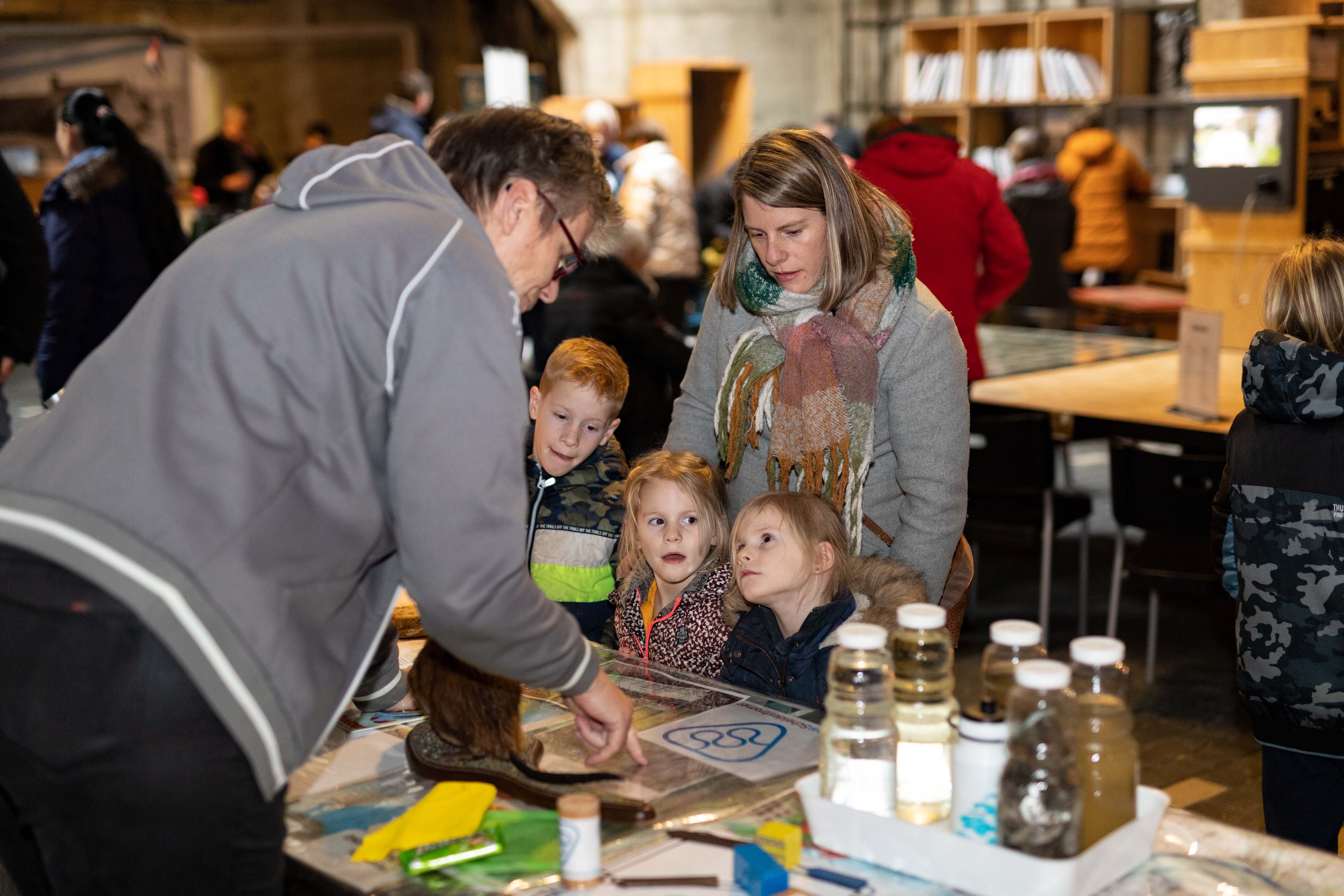 Kinderen kijken naar een vrouw die iets uitlegt.