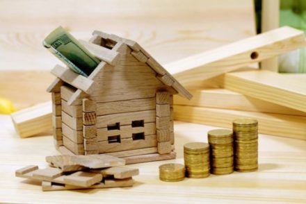 Afbeelding van een houten huisje met geld, ter illustratie van de erfpacht van een woning