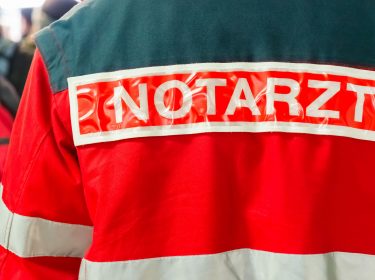 Ein Notarzt, dessen Jacke mit Aufschrift man von hinten sieht.