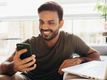 Mann setzt sein Android-Smartphone zurück und lächelt