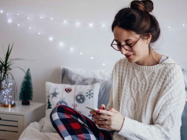 Junge Frau informiert sich am Smartphone über iPhone-7-Tricks.