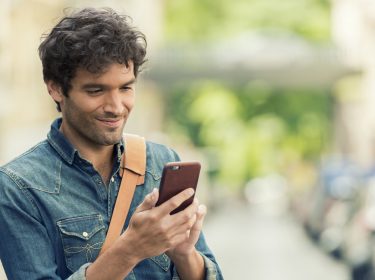 Mann liest Facebook-Nachrichten auf seinem Smartphone