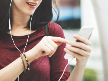 Frau hört mit Kopfhörern Musik auf dem Smartphone