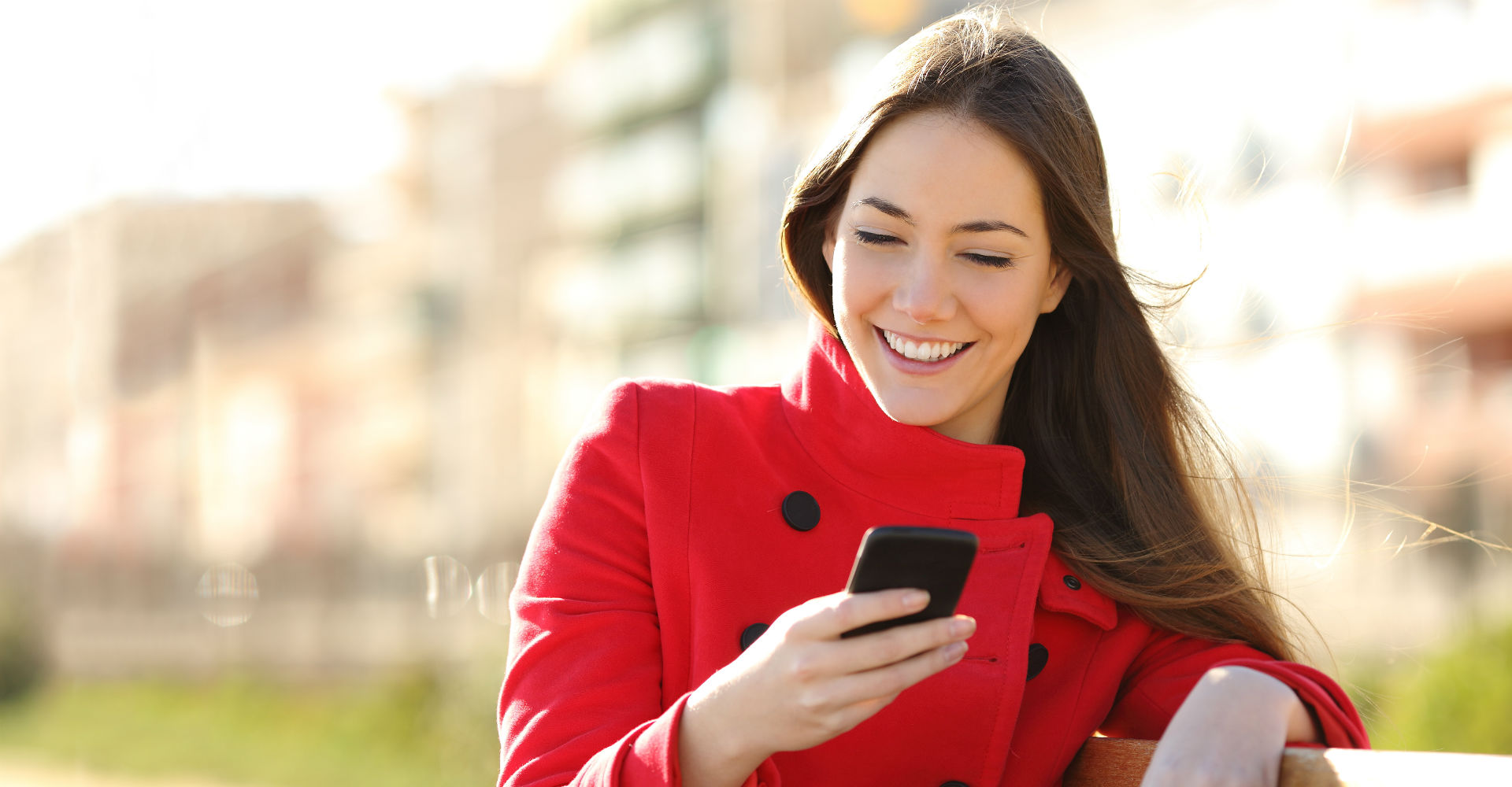 Frau im roten Mantel mit Smartphone in der Hand