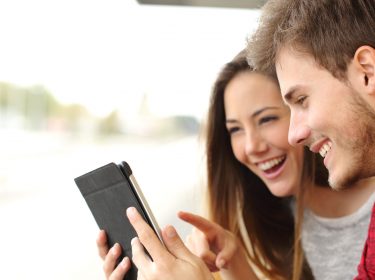 Junges Paar spielt draussen auf dem iPad