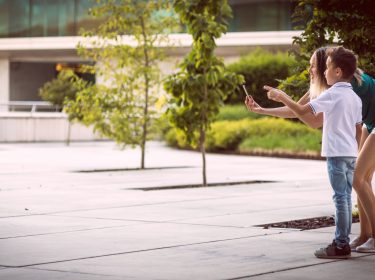Junge Frau und Kind betrachten Betonwüste durch ein Smartphone