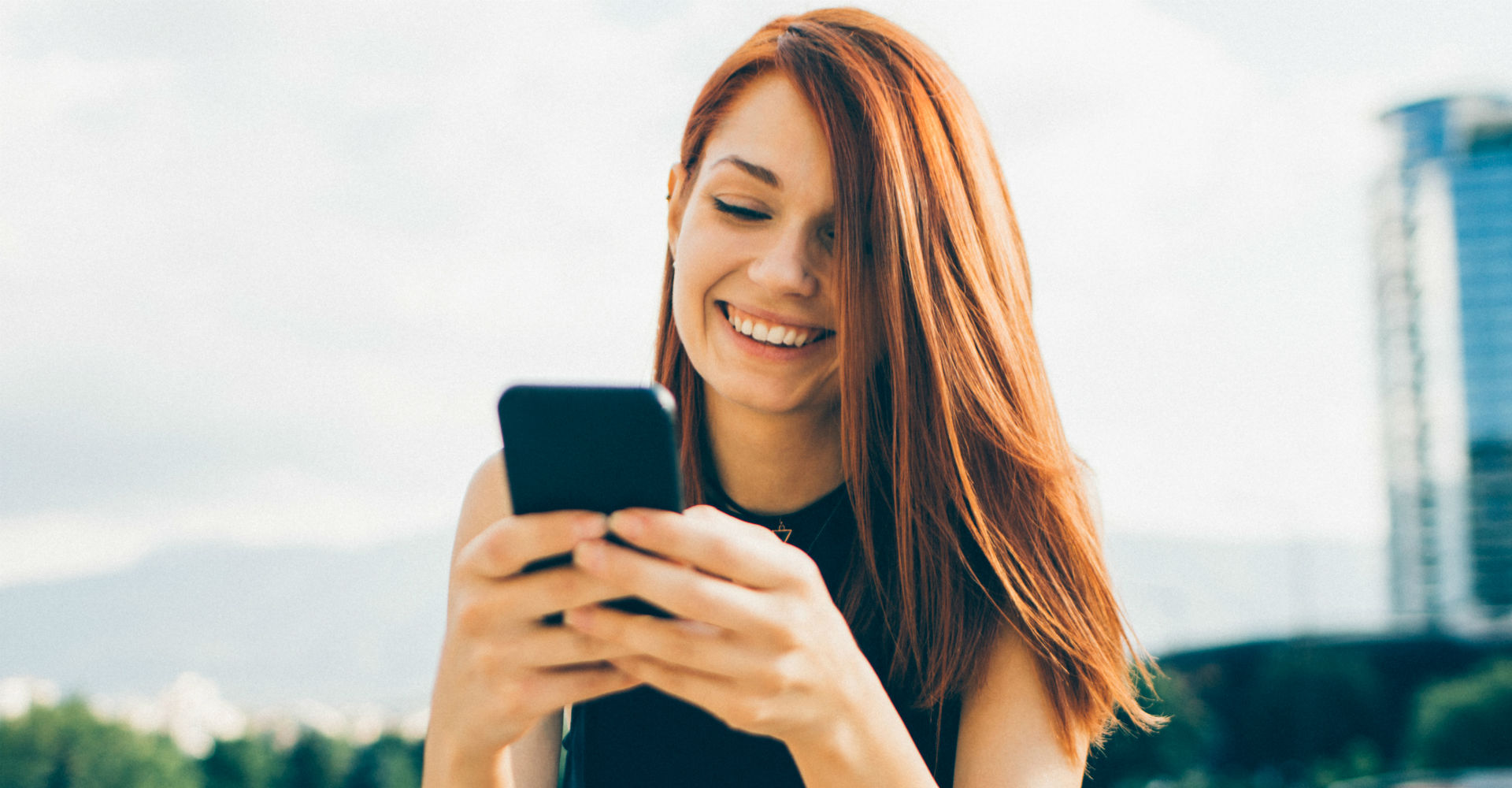 Rothaarige Frau mit Smartphone in der Hand