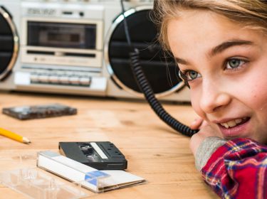 Mädchen hört Audiokassette auf altem Abspielgerät