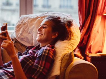 Frau tippt zu Hause am iPhone.