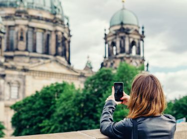 Frau schießt ein Foto vom Berliner Dom mit dem Smartphone