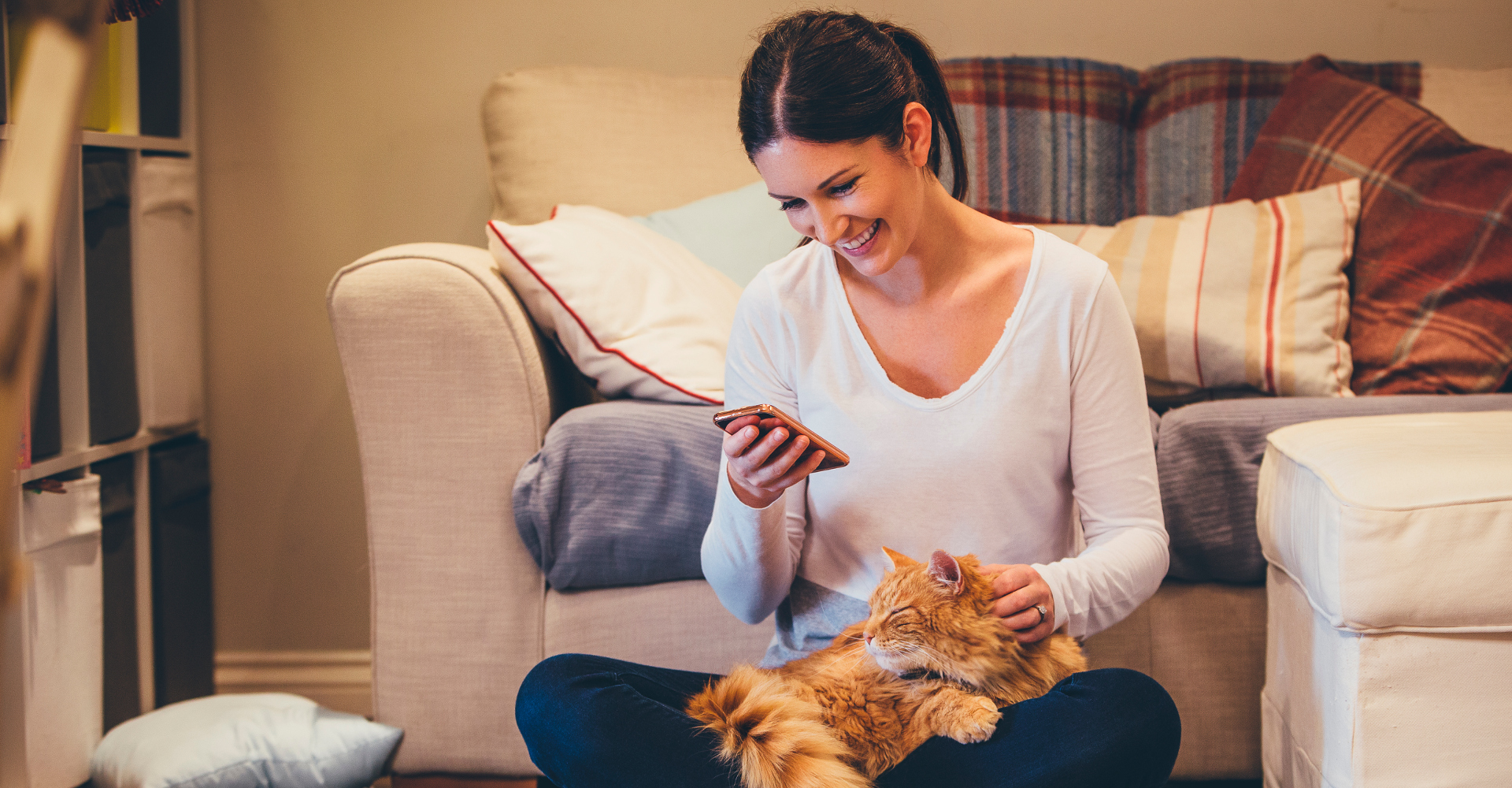 Frau mit Katze schaut auf Smartphone.