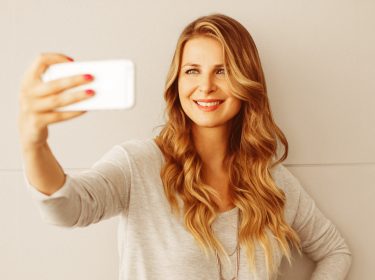 Frau schaltet Smartphone mit Gesichtserkennung frei.