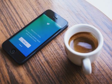 Smartphone auf dem Tisch mit Twitter-Oberfläche und Kaffee