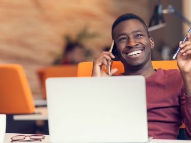 Junger Mann telefoniert lächelnd mit dem Android-Smartphone.