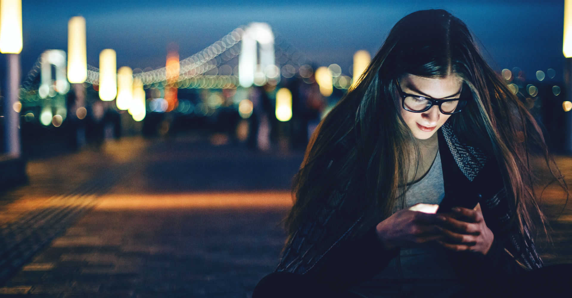 Junges Mädchen schaut auf ihr Smartphone in der Nacht.