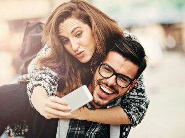 Junger Mann trägt Frau Huckepack.