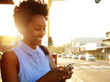 Frau mit Smartphone im Sonnenuntergang.