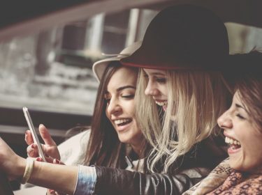 Drei Freundinnen lachen zusammen.