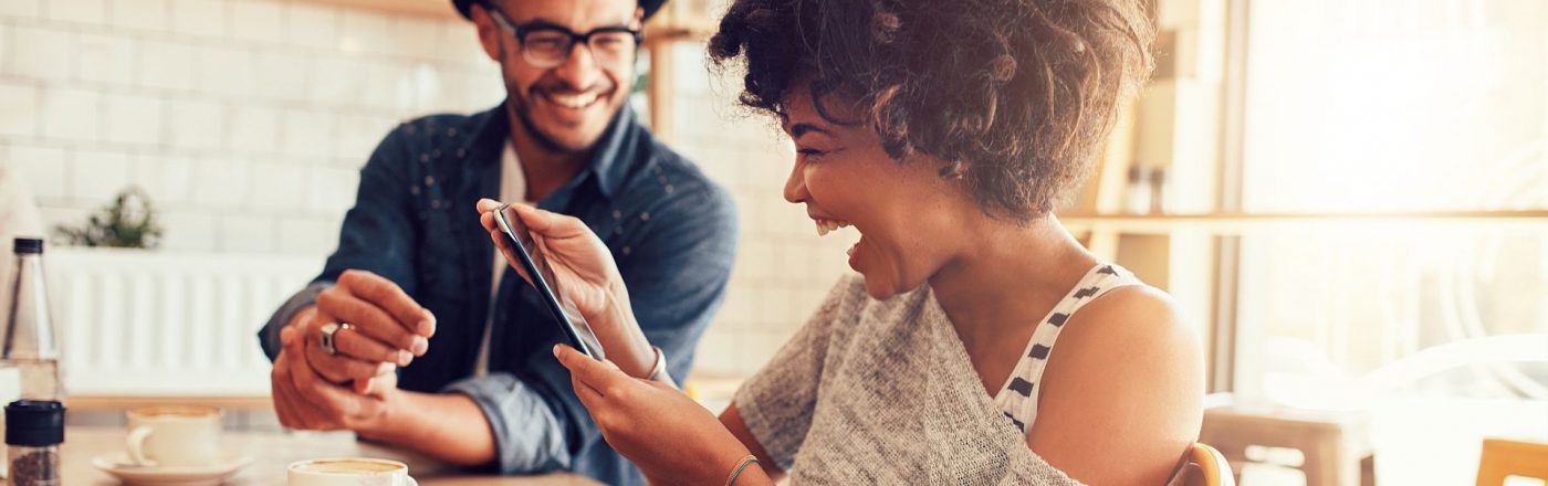 Lachende Frau mit Smartphone im Cafe