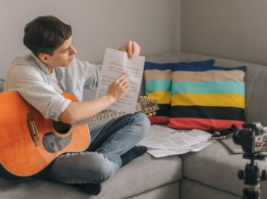 Junger Mann mit Gitarre filmt sich selbst