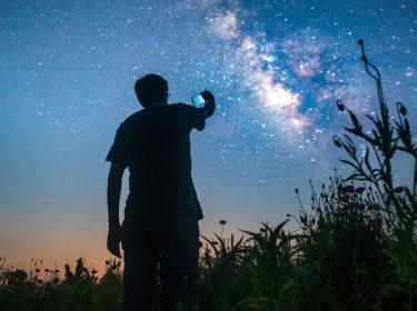 Mann fotografiert die Sterne mit dem Handy.