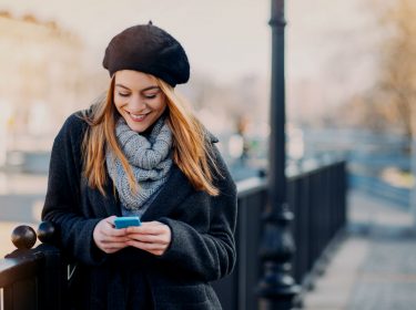 Frau mit iPhone auf Brücke