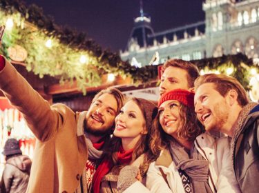 Freunde machen Selfie von sich auf einem Weihnachtsmarkt.