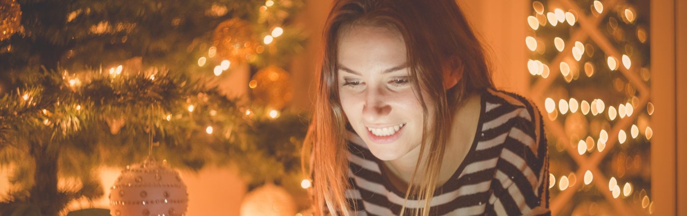 Weihnachtsgrüsse kannst Du ganz leicht via App erstellen und versenden Eine Frau verschickt Weihnachtsgrüße via Smartphone