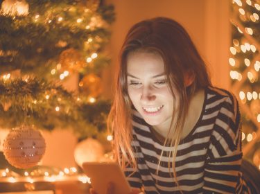 Eine Frau verschickt Weihnachtsgrüße via Smartphone
