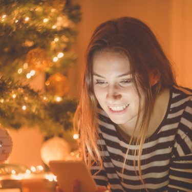 Weihnachtsgrüsse kannst Du ganz leicht via App erstellen und versenden Eine Frau verschickt Weihnachtsgrüße via Smartphone