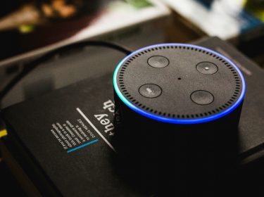 Der schwarze Amazon Echo Dot auf einem Stapel Bücher.