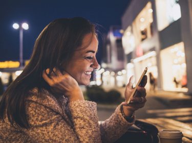 Junge Frau checkt ihre Mails am Smartphone.