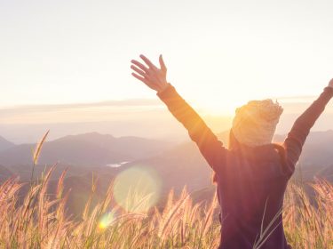 Junge Frau genießt ihre Freiheit vor einer Landschaftskulisse