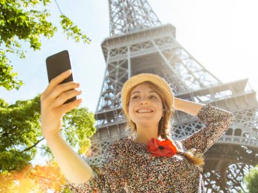 Eine Frau macht ein Selfie am Eiffelturm in Paris